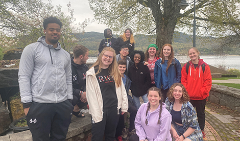 A group of students smiles in front of nature