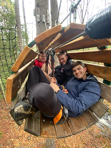 Students smile in wooden tunnel swing