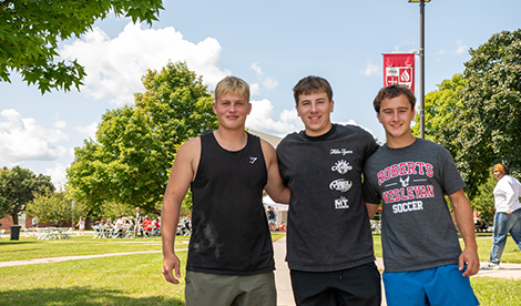 3 students smile on campus