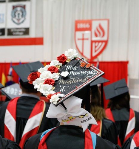 A decorated grad cap with flowers and a butterfly. It also says 