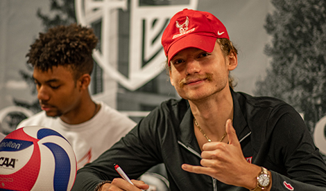 Alexander signs wears a Red Redhawks hat when signing on the volleyball team.