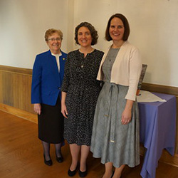 3 women stand and smile.