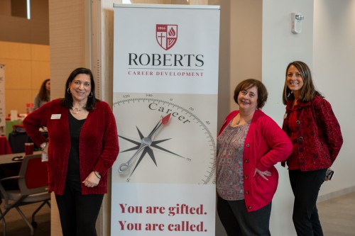 The members of the Career Development office smiles next to their sign