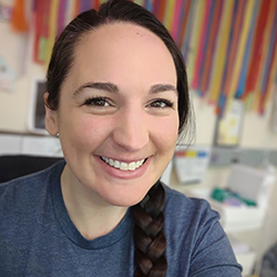 A young woman with dark hair in a braid smiles.