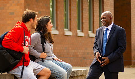 Dr. Hayles talks with 2 students. All 3 smile.