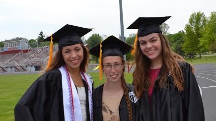 Gabby smiling at graduation with 2 classmates