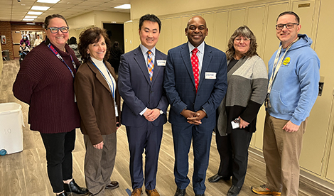 6 adults, including Dr. Rupert A. Hayles Jr. and Matt Zager stand and smile.