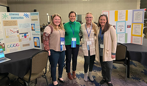 Elizabeth Volpe, faculty member Elizabeth Stevens, student Sophie Farnholz, and Barrett smile in front of poster boards at the NYSRA conference