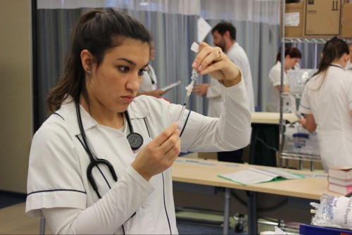 A nursing student measures some medicine.