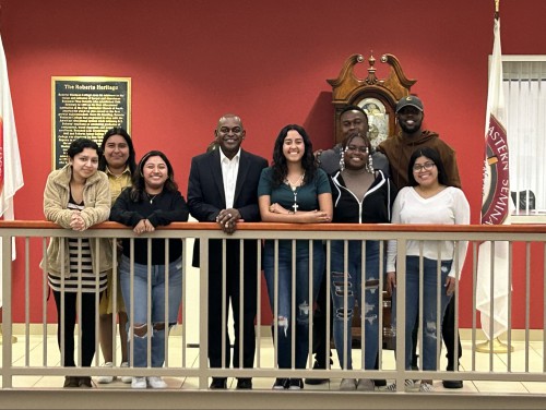 Dr. Hayles stands and smiles with students.