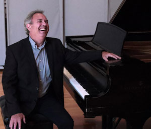 Stephen Shewan smiles while sitting at piano