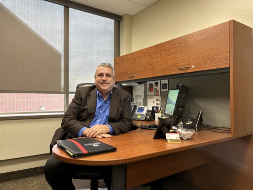 Steven sits at his desk and smiles.