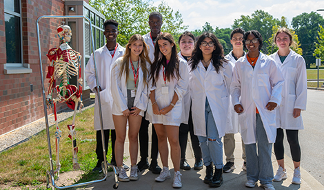 Student at summer camp wear white jackets and smile.