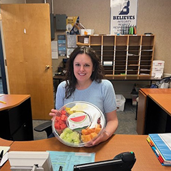 Teacher sitting receiving a fruit bowl.