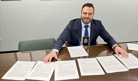 Tyler Dawson smiles with papers spread out before him.