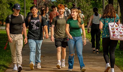 4 students walk on campus toward the camera.