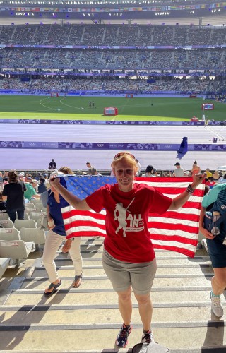 Wendy smiles with the American flag in Paris at the Olympic track and field stadium