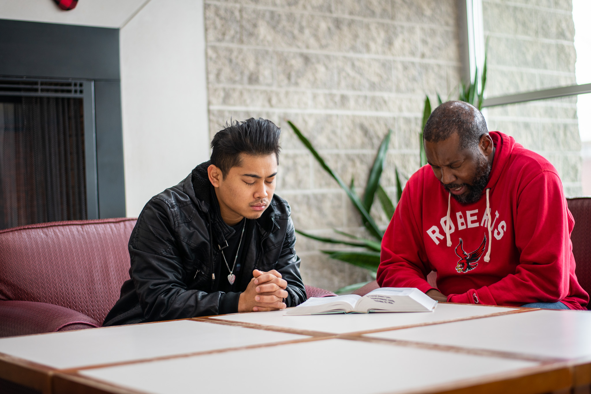 A Roberts Wesleyan University student and pastor pray together